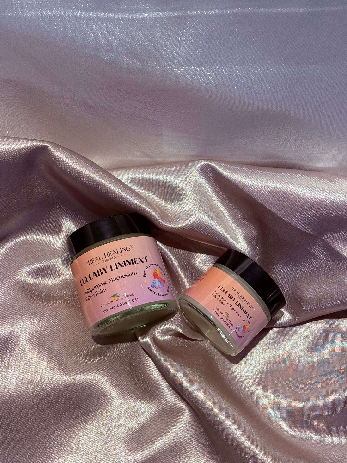 Lullaby Liniment Magnesium Tallow Balm jars on soft satin fabric, showcasing soothing and relaxing skincare products.